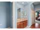 A well-lit bathroom features a vanity with a tan countertop and cabinet, a large mirror, and blue walls at 11949 Wexford Blvd, Spring Hill, FL 34609