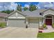 A large three-car garage with light gray doors and a concrete driveway leading to the home at 11949 Wexford Blvd, Spring Hill, FL 34609