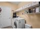 Bright laundry room with a modern washing machine, dryer, storage shelf, and a tiled floor at 11949 Wexford Blvd, Spring Hill, FL 34609