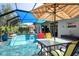This screened-in patio is equipped with a pool, dining set, and a blue awning to provide ample shade at 11949 Wexford Blvd, Spring Hill, FL 34609