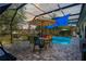 The screened-in patio boasts a pool, seating area, blue awning, and views of the manicured backyard at 11949 Wexford Blvd, Spring Hill, FL 34609