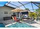This covered patio with a dining set and swing overlooks the pool and surrounding yard in the fenced backyard at 11949 Wexford Blvd, Spring Hill, FL 34609