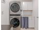 A modern laundry room features stacked washer and dryer, white cabinetry and counter space for organizing and folding at 13160 Golden Lime Ave, Spring Hill, FL 34609