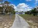 Front exterior view of the property, featuring a long driveway and fenced yard at 13377 Montour St, Brooksville, FL 34613
