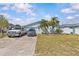 Exterior of a light blue home with a spacious driveway, tropical landscaping at 13815 Plumosa Ave, Hudson, FL 34667