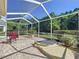 Screened-in patio features brick floor, a relaxing sitting area, and lush green landscaping at 16022 Westerham Dr, Tampa, FL 33647