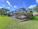 Backyard featuring a screened lanai, manicured landscaping, and beautiful lush lawn at 16022 Westerham Dr, Tampa, FL 33647