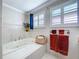 This bathroom features a soaking tub with tile surround and white shutters for a bright, clean finish at 16022 Westerham Dr, Tampa, FL 33647
