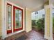 Covered entryway featuring a red-framed glass door and brick flooring with a small welcome mat at 16022 Westerham Dr, Tampa, FL 33647