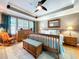 Main bedroom featuring hardwood floors, tray ceilings, a ceiling fan and a large window at 16022 Westerham Dr, Tampa, FL 33647