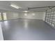 Spacious garage featuring a large gray epoxy floor, windows and double glass doors at 18232 Monteverde Dr, Spring Hill, FL 34610