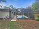 Backyard view with a screened-in pool, lush greenery, and a charming exterior at 18232 Monteverde Dr, Spring Hill, FL 34610