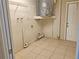 A well-lit utility room featuring a water heater and white tiled flooring at 18232 Monteverde Dr, Spring Hill, FL 34610