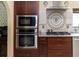 Kitchen with stainless steel appliances, built-in microwave and oven, tile backsplash and custom cabinetry at 22106 Garmisch Way, Brooksville, FL 34601