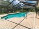 Enclosed kidney-shaped pool, surrounded by a brick patio and mature landscaping at 22106 Garmisch Way, Brooksville, FL 34601