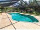 Backyard view of kidney-shaped pool with screened enclosure and various patio furniture at 22106 Garmisch Way, Brooksville, FL 34601