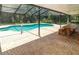 Screened-in pool with a brick deck, table with benches, and mature trees in background at 22106 Garmisch Way, Brooksville, FL 34601