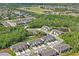 An aerial view of a townhome community surrounded by green spaces, ponds, and mature trees at 3032 Jacob Crossing Ln, Holiday, FL 34691