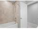 Bathroom shower with beige tile surround and modern showerhead and hardware with white door entrance at 3032 Jacob Crossing Ln, Holiday, FL 34691