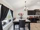Bright dining area featuring dark wood table and chairs, stylish lighting fixture, and a large window with backyard views at 3455 Whispy Ct, Spring Hill, FL 34609