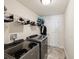 Well-equipped laundry room featuring modern washer and dryer, storage shelves and tile floor at 3455 Whispy Ct, Spring Hill, FL 34609