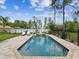 Refreshing backyard pool with a fountain, surrounded by lounge chairs, and framed by mature trees and a fence at 3455 Whispy Ct, Spring Hill, FL 34609