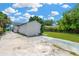 View of the backyard and driveway featuring grass, a white stucco wall, and partial blue sky at 4035 Fairfield S Ave, St Petersburg, FL 33711