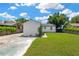 Backyard of home featuring grassy lawn and concrete driveway under a partly cloudy blue sky at 4035 Fairfield S Ave, St Petersburg, FL 33711