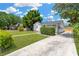 Charming home with landscaped front yard featuring mature trees, green lawn, and concrete driveway at 4035 Fairfield S Ave, St Petersburg, FL 33711