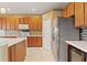 Modern kitchen features stainless steel refrigerator, white countertops, wood cabinets, and tile backsplash at 4335 Canongate Ct, Spring Hill, FL 34609