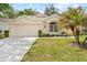 Traditional home with a manicured lawn, a two-car garage, and a lovely front yard palm tree at 4407 Caliquen Dr, Brooksville, FL 34604