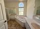 Light-filled primary bath with dual vanities and garden tub under a large window at 4450 Anaconda Dr, New Port Richey, FL 34655