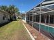 Back exterior of the home showing a screened-in pool area and lush greenery at 4450 Anaconda Dr, New Port Richey, FL 34655