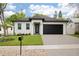 Charming single-story home featuring a manicured lawn, black garage door, and sleek modern design at 461 Pent St, Tarpon Springs, FL 34689