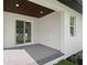 A covered patio area, with brick pavers, overlooking a lawn with mature landscaping and a sliding glass door at 461 Pent St, Tarpon Springs, FL 34689