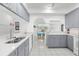 Bright kitchen features gray cabinets, quartz countertops, stainless steel sink and white tile floors at 473 Tournament Dr, Spring Hill, FL 34608