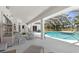 Open-air lanai with ample seating overlooks a sparkling pool and serene, treelined backyard at 473 Tournament Dr, Spring Hill, FL 34608