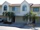 Townhouse exterior with multiple garages, palm trees, and arched windows at 545 Walden Ct, Dunedin, FL 34698