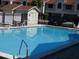 Relaxing swimming pool surrounded by lounge chairs and a glimpse of the community buildings at 545 Walden Ct, Dunedin, FL 34698