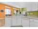 Bright kitchen features white cabinets, breakfast bar, and vibrant orange and green walls at 6109 Japonica Ct, New Port Richey, FL 34655