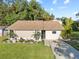 Well-maintained home featuring a manicured lawn, mature trees, and a paved driveway at 7101 N 18Th St, Tampa, FL 33610