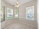Bright dining room with neutral tile flooring, ceiling fan, and three large windows at 7427 Wimpole Dr # 7427, New Port Richey, FL 34655