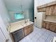 Traditional-style kitchen featuring wood cabinets, tile floors, and double sink overlooking the living area at 7444 Candlelight Ct, New Port Richey, FL 34652