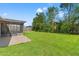 Large backyard showing a screened-in porch with view of lawn, fence and trees at 8341 Corney Dr, Port Richey, FL 34668