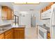 Open kitchen with white appliances, tile flooring, wooden cabinets, and ample counter space at 8341 Corney Dr, Port Richey, FL 34668