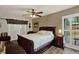 Comfortable bedroom with hardwood floors, ceiling fan, and view to outdoors through shuttered window at 8516 Wooddrift Dr, Tampa, FL 33615