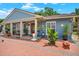 Charming home with brick facade, red door, a covered porch with outdoor seating and mature landscaping at 8516 Wooddrift Dr, Tampa, FL 33615