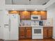Bright kitchen featuring wood cabinetry, white appliances, and tile backsplash at 9398 Mississippi Run, Weeki Wachee, FL 34613