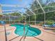 Sparkling pool surrounded by a screened enclosure, landscaping and deck chairs at 9398 Mississippi Run, Weeki Wachee, FL 34613