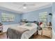 This blue bedroom features a ceiling fan, multiple windows, and stylish decor and furnishings at 10134 Buck Dr, New Port Richey, FL 34654